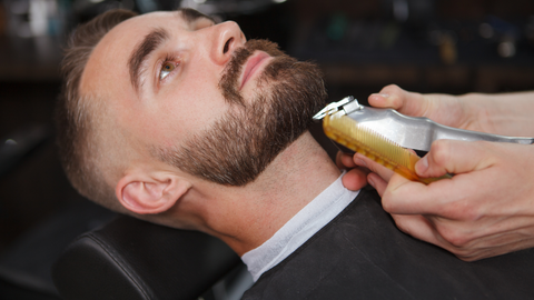 A man getting a beard fade by a barber.