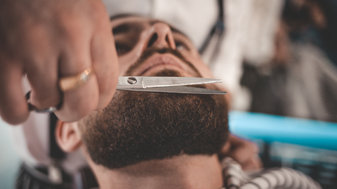 A man having his boxed beard style groomed at a barbershop.