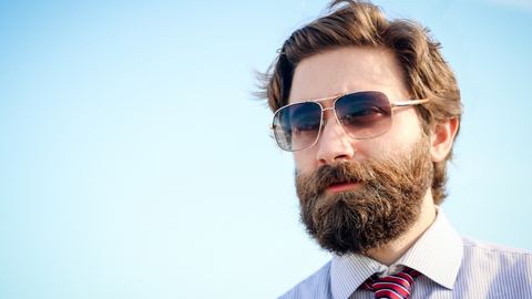 A man wearing sunglasses with a scruffy short beard style.