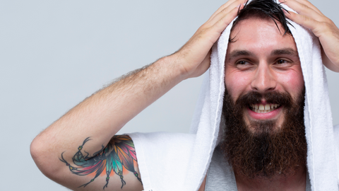 A bearded man towel drying his hair.