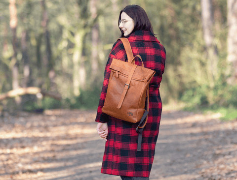 Frau mit rotem Mantel trägt den DONALD Rucksack während eines Spaziergangs im Wald
