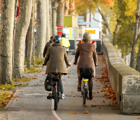 Two women biking outdoors in autumn on urban bike path