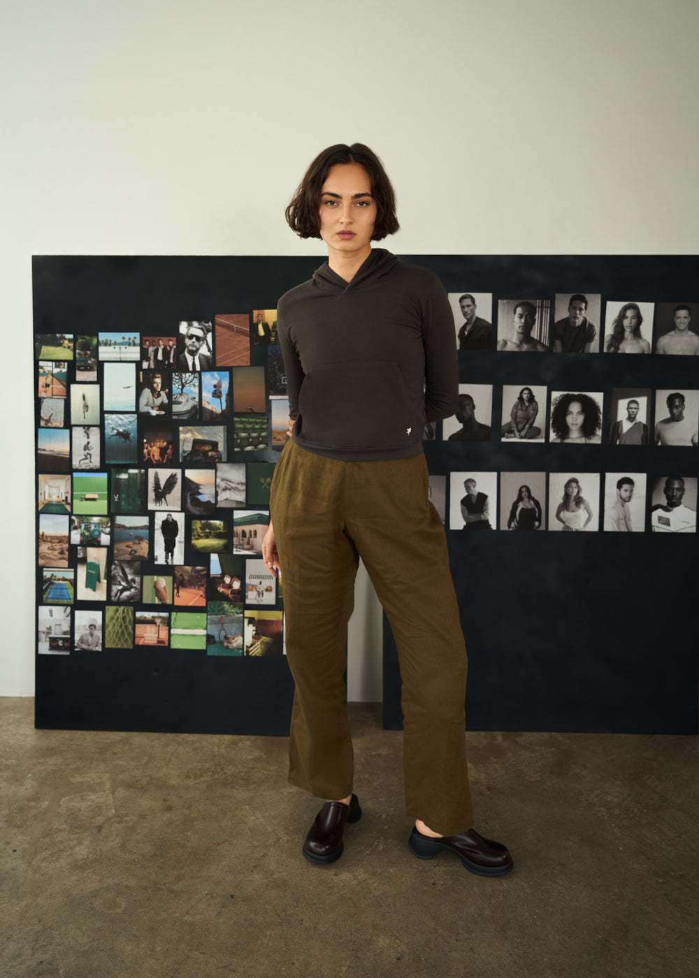 Woman standing in front of a photo collage wall.