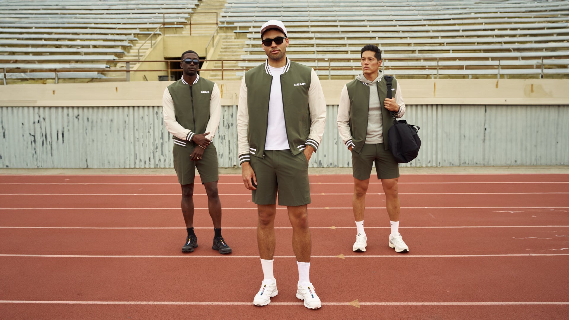 Three men in athletic wear posing on a track field.