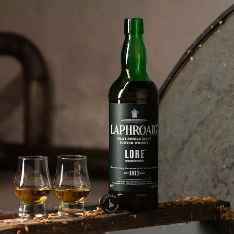 "Flaske af Laphroaig Lore Single Malt Whisky med karakteristisk mørk etiket, fremvist foran en baggrund, der afspejler Islay's robuste kystlandskab, illustrerer whiskyens rige og røgede arv.
