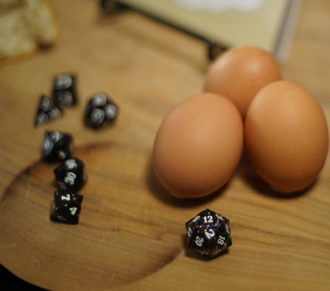Three eggs placed gently alongside some tastefully strewn dice, with a D20 in the foreground reading the number 12, for some unknown reason.