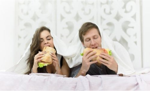 Woman and man eating in bed