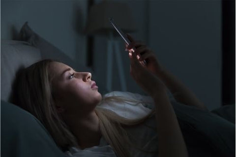 Woman staring at phone before bed