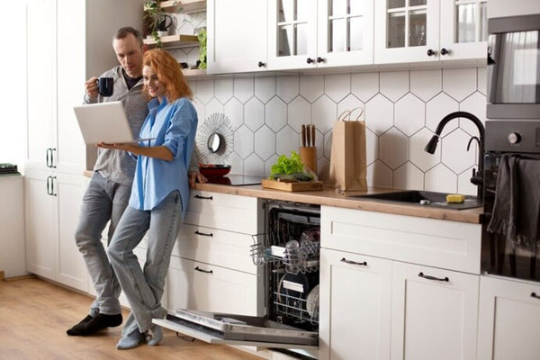 Pareja comprobando lo que consumen sus electrodomésticos en la cocina.