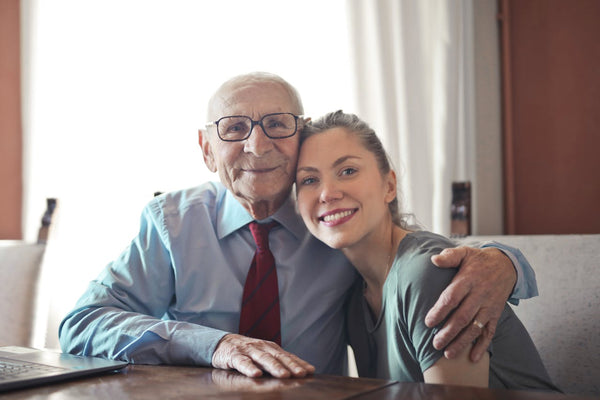Senior man with his arm around his caregiver, smiling.