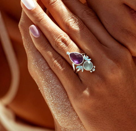 amethyst and aquamarine celestial silver ring on the sandy hands of a boho beach girl