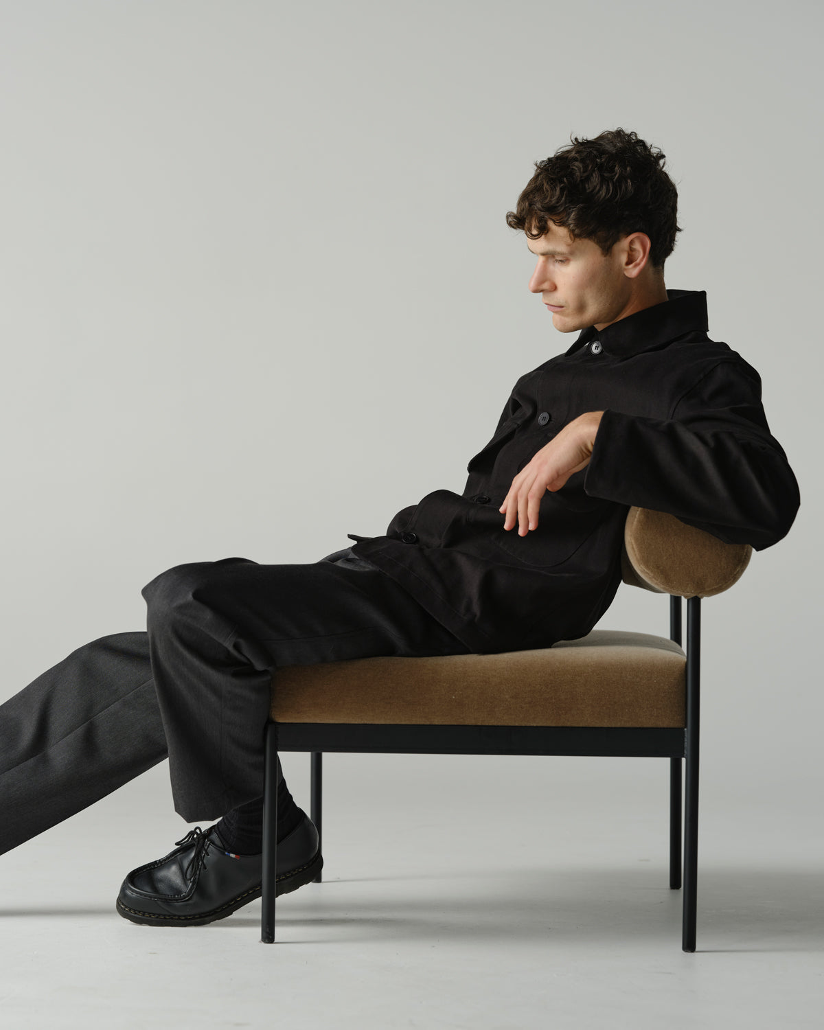 Male model sitting on chair wearing a black jacket and charcoal trouser