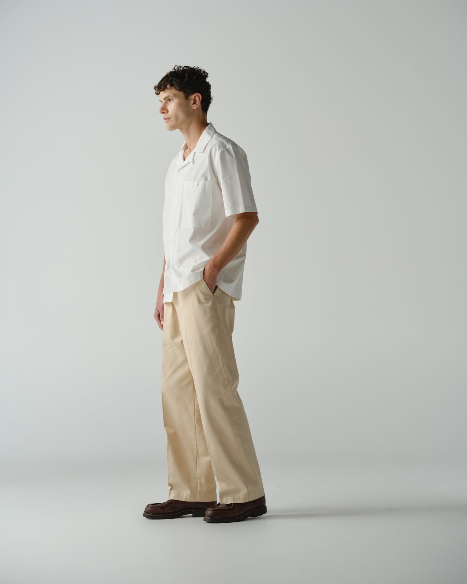 Side view of male model wearing a almost white Cocktail Shirt and Wide Pant in Ecru