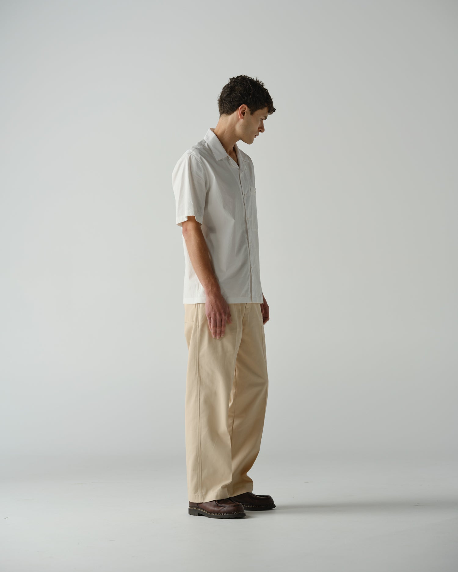 Side view of male model wearing a almost white Cocktail Shirt and Wide Pant in Ecru