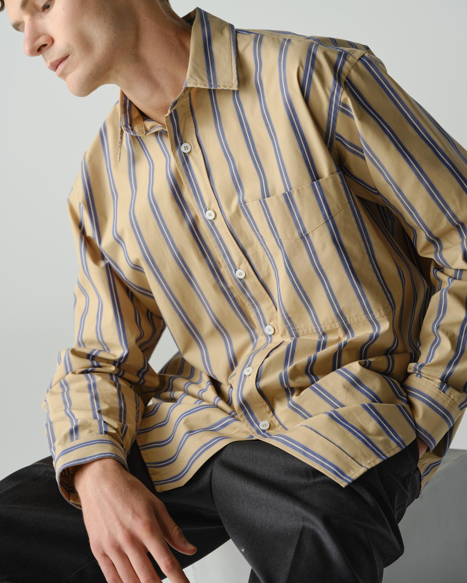 Close up of man wearing a striped oversized long sleeve shirt