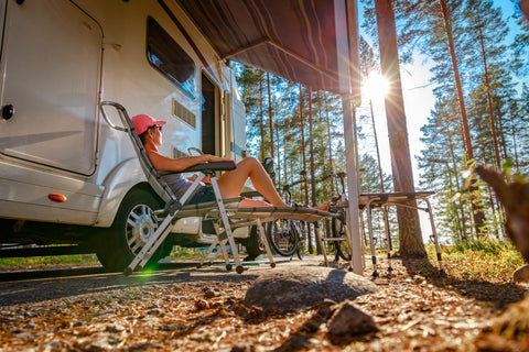 Femme étendu sur une chaise en nature devant son véhicule récréatif