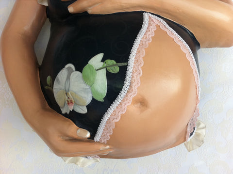 gipsabdruck babybauch mit zwei armen auf bauch mit orchideen