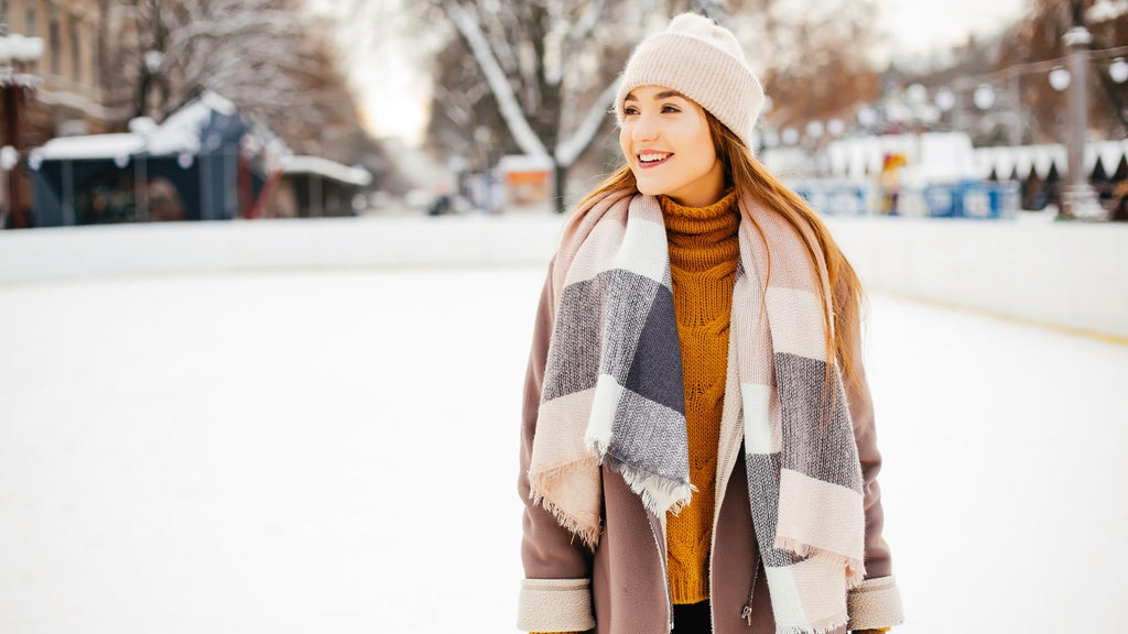 Smiling woman in winter clothing, enjoying the outdoors, representing the joy of natural skin care in winter settings.