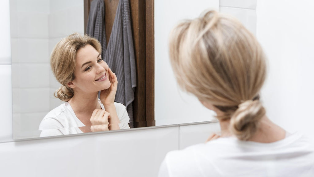 Mature woman examining her face in the bathroom mirror, reflecting on her skincare routine