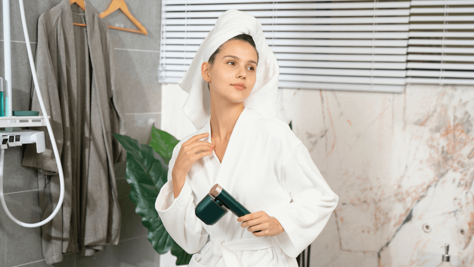 Woman in white bathrobe holding an IPL hair removal device in a modern bathroom setting.