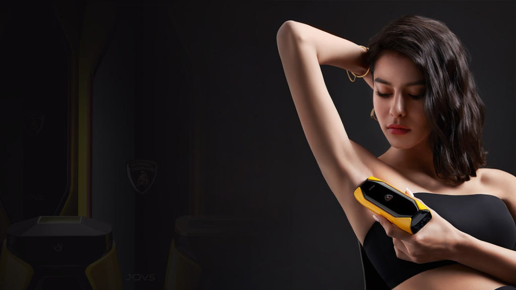 A woman using a JOVS X 3-in-1 IPL Hair Removal Device on her underarm in a dark setting.