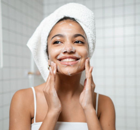 A woman smiles as she washes her face