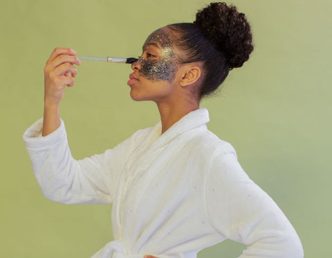 A woman applies a face mask with a makeup brush.