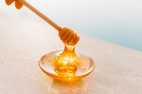 A thick stream of honey being lifted from a dish.