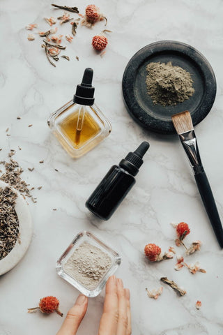 Various essential oils, powders, and dried plants on a table