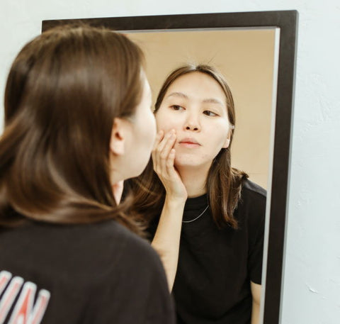 A woman studies her face in the mirror