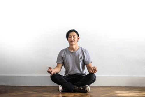 A guy meditating in an empty room