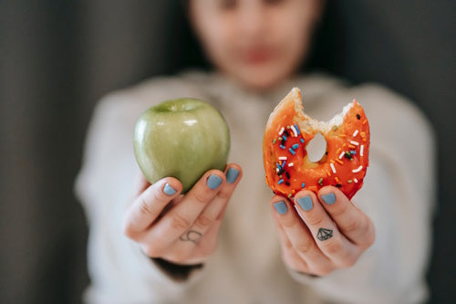 Person comparing a donut and an apple