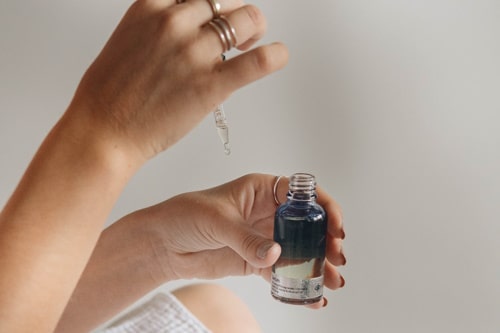 Woman getting skin serum from bottle