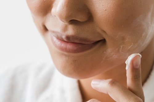 Woman moisturizing her face