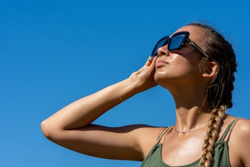 A beautiful young woman in sun glasses looks up 