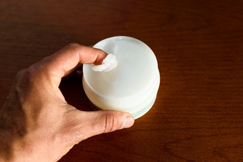A man picks up white vaseline to moisturize his skin