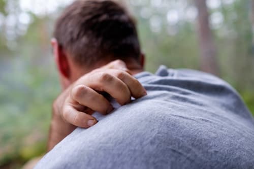 Guy with grey shirt scratching his back