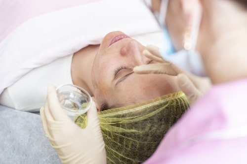 A professional cosmetologist applies a chemical peel