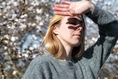 Young woman covering her eyes due to sunlight