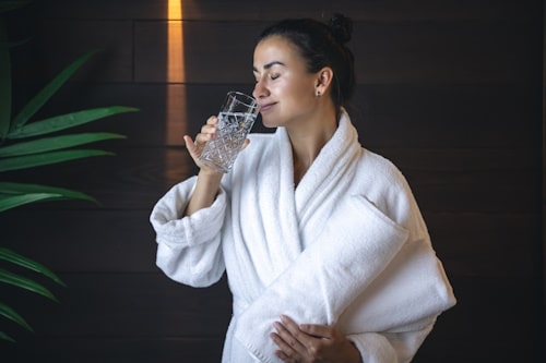 A young woman with a glass of water after the sauna