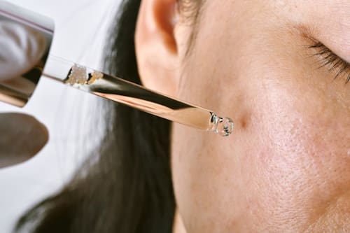 Woman using dropper to put oil on face