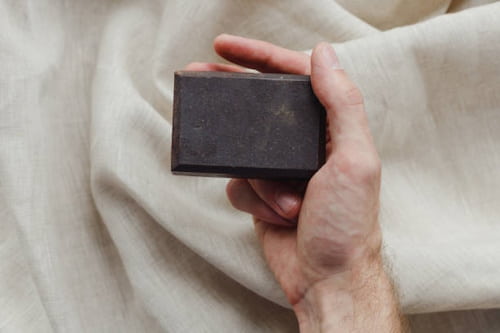 Male hands holding activated charcoal soap