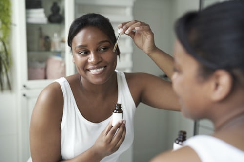 Woman looking at mirror using spot acne treatment