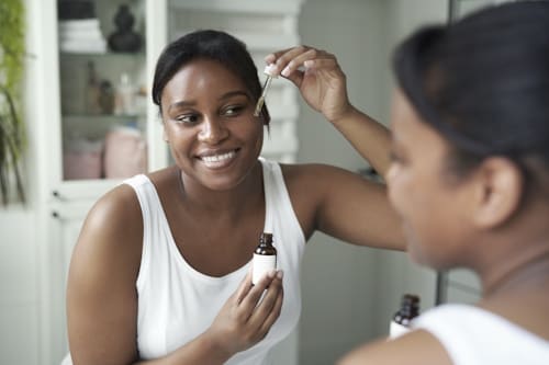 Woman applying herb extract on her face