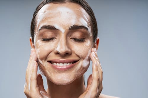 Woman washing her face with a cleanser soap