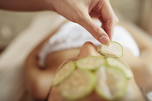 Woman lying down with cucumber on face