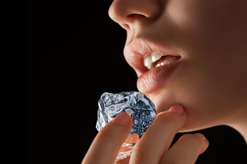 Woman rubbing ice on chin acne