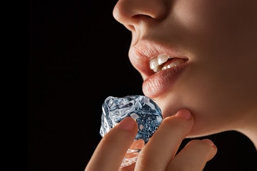 Woman applying ice on her chin acne