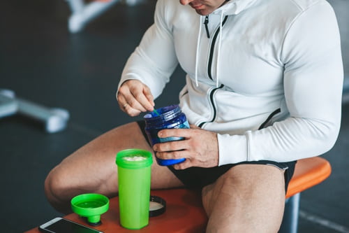 Athletic male body builder scooping up pre workout powder