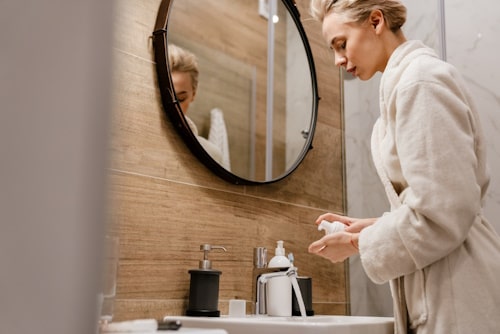 Attractive young woman applying moisturizer on her face